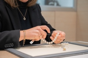 Mitarbeiterin erstellt eine Perlenkette.